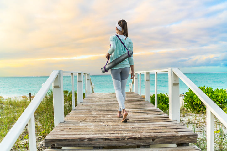 Woman carrying a yoga mat with a yoga sling to the beach